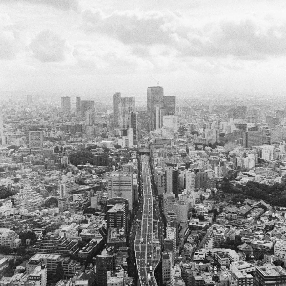 High-contrast black and white photograph of a cityscape captured on Ilford HP5+ film, featuring bold lines and shapes with a timeless and classic aesthetic.
