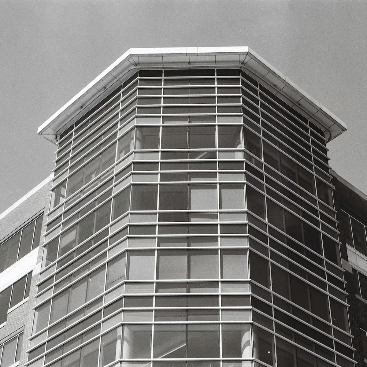 Minimalist black and white photograph of a modern building captured on Ilford Delta 100 film, featuring fine details and smooth tonal transitions with a crisp and clean feel.